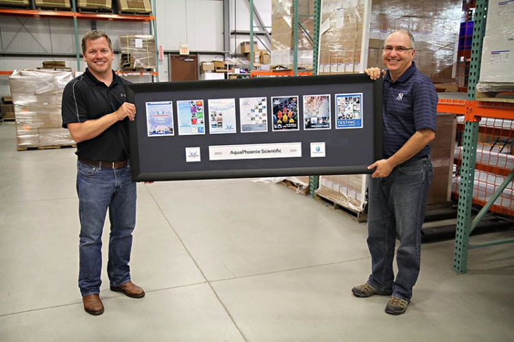 two AquaPhoenix employees holding up a picture commemorating the company's 10 year anniversary